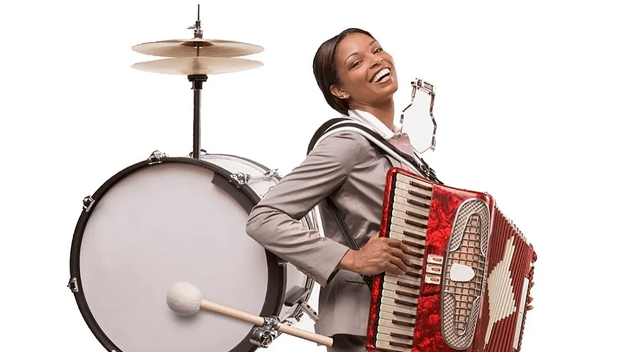 Femme au sourire forcé jouant simultanément de l'accordéon et de la grosse caisse de batterie (faisant un 'homme orchestre'), illustrant la surcharge du multi-projet.